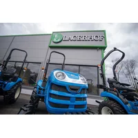 Text: Small LS tractor in front of Lagerhof